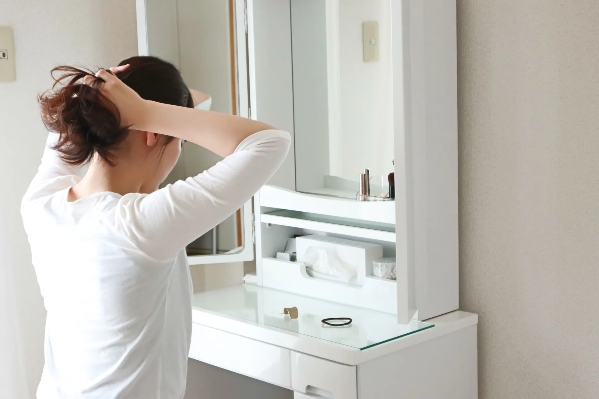 洗面台で髪を結んでいる女性