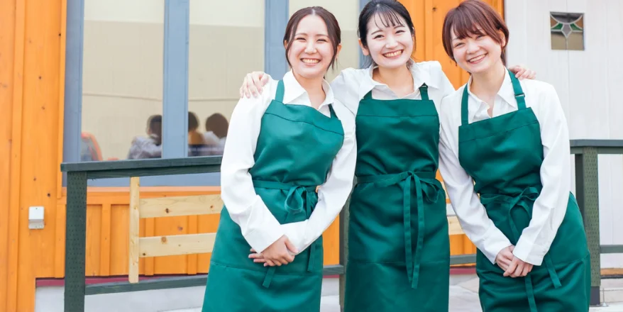 肩を組みほほんでいる女性3人