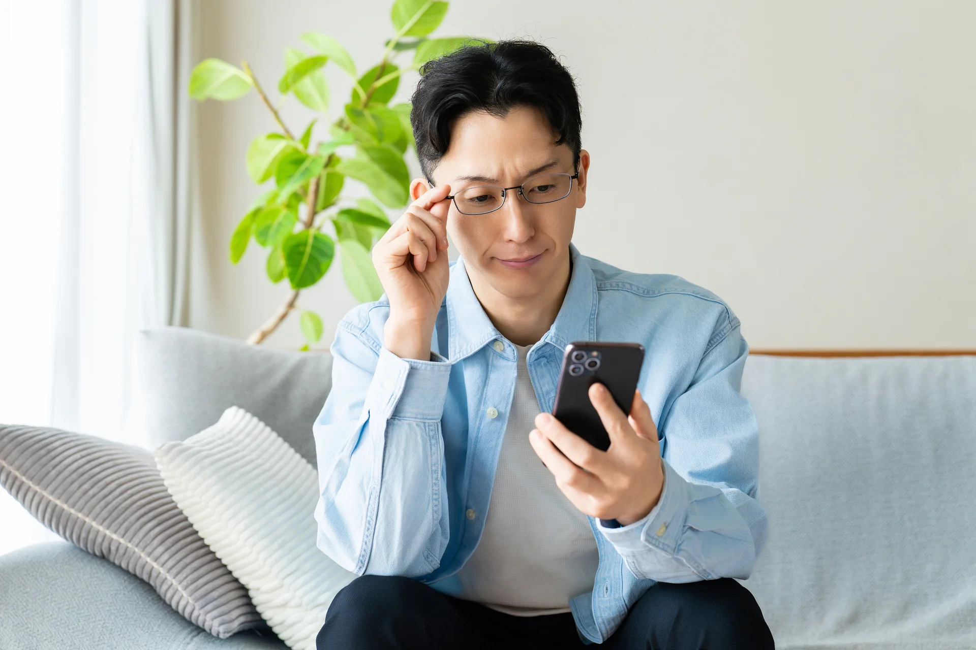 メガネをかけている男性が、真剣にスマートフォンを見ている様子