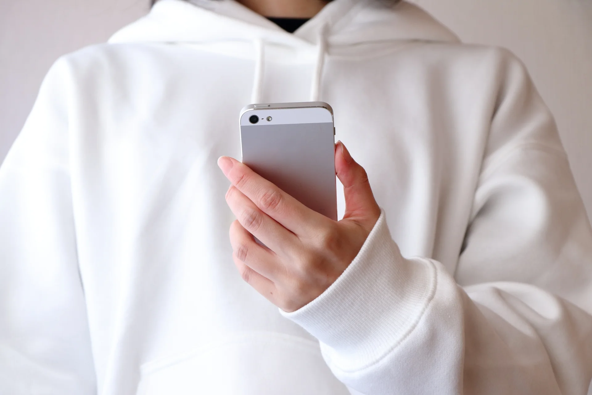 片手でスマートフォンを見ている人物