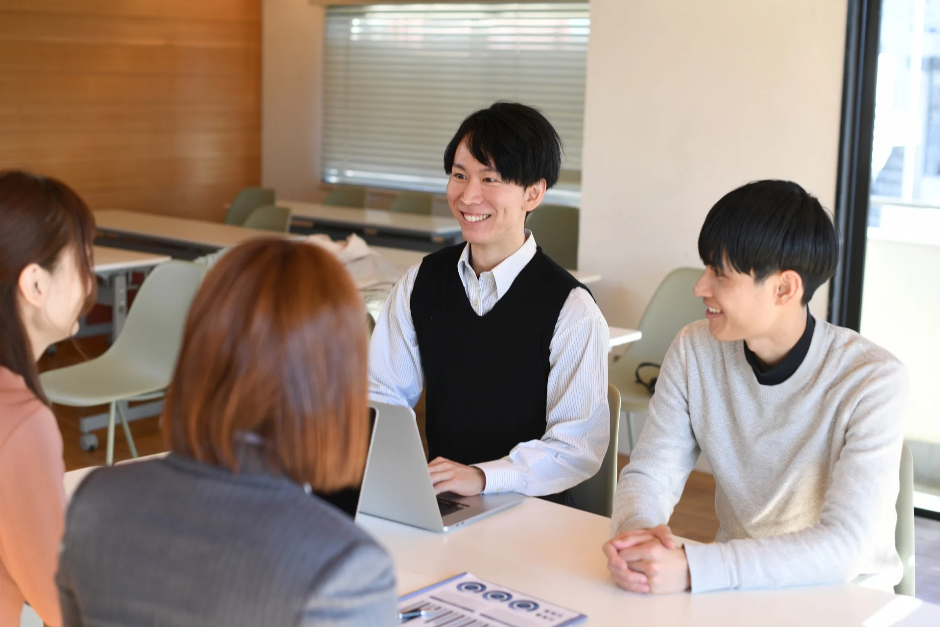 男女4人が、学校のカフェで話している様子